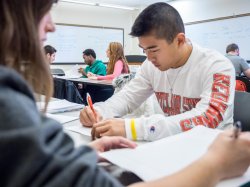 photo of student at desk writing wearing Montclair State shirt