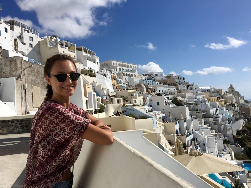 Student posing on balcony in Grecian cliffside town